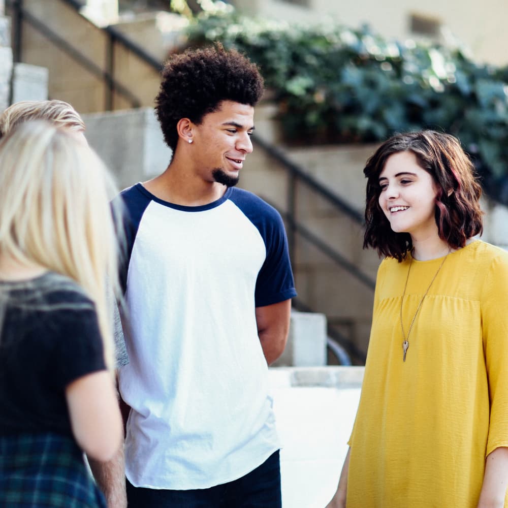 Three teens stand in a circle and laugh together.