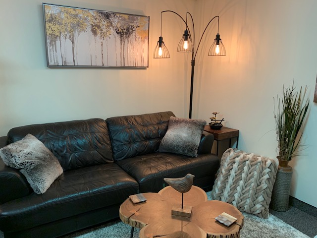 Adult therapy office with black leather couch and wooden coffee table.