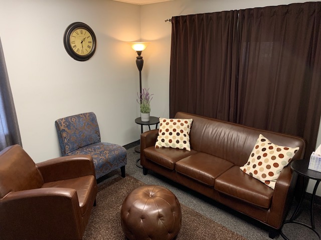 Adult therapy office with brown leather chair and couch.